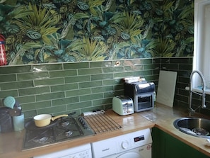 A kitchen with a gas stove, a toaster, a microwave, and a sink.