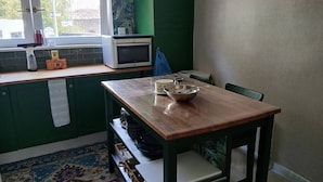 Una cocina con una mesa de madera, un microondas y una ventana con vistas.