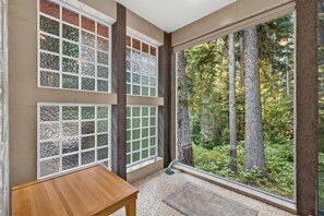 A room with large windows, a wooden table, and a view of a forest. - Creekside Inn- sleeps 6, pets ok-  perfect private getaway (McCall)