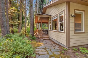 A cabin with a stone pathway leading to a covered porch with outdoor seating.