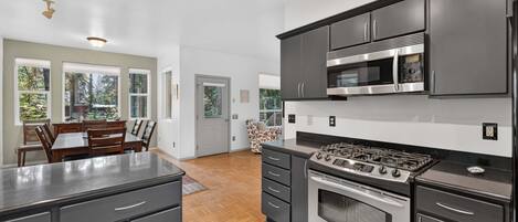 Una cocina moderna con estufa a gas, microondas y muebles oscuros.