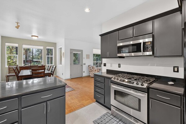 A modern kitchen with a gas stove, microwave, and dark cabinetry.