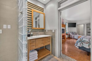 A modern bathroom with a glass shower enclosure, wooden vanity, and a large mirror. - Creekside Inn- sleeps 6, pets ok-  perfect private getaway (McCall)