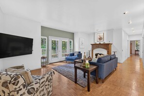 A spacious living room with a fireplace, a blue sofa, and a television mounted on the wall.