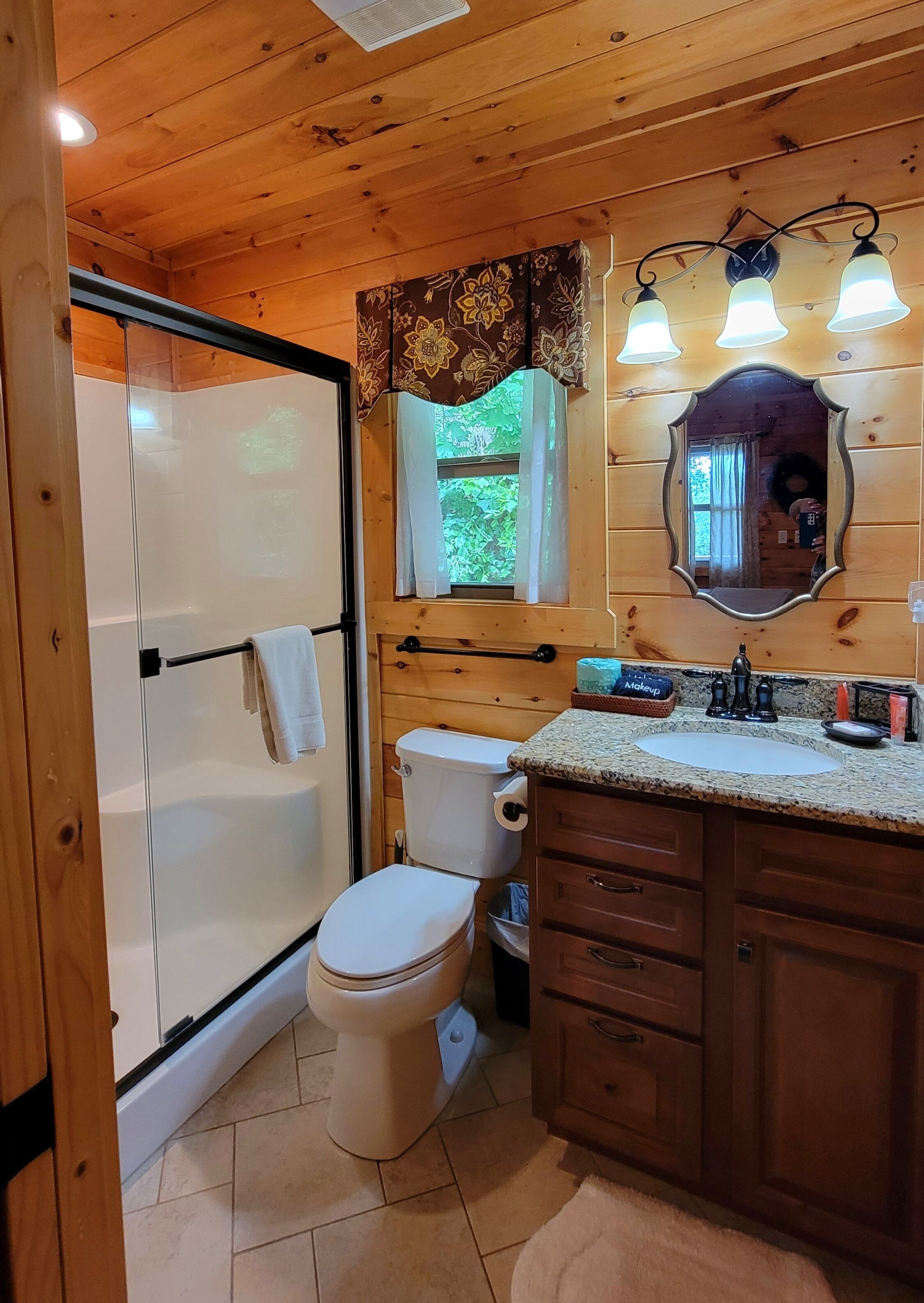 Ein Badezimmer mit Dusche, Toilette, Waschbecken und Holzschränken.