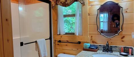 Ein Badezimmer mit Dusche, Toilette, Waschbecken und Holzschränken.