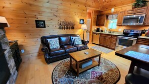 Ein Holzinterieur mit einer Ledersofa, einem Holztisch und einer Küchenzeile mit modernen Geräten.