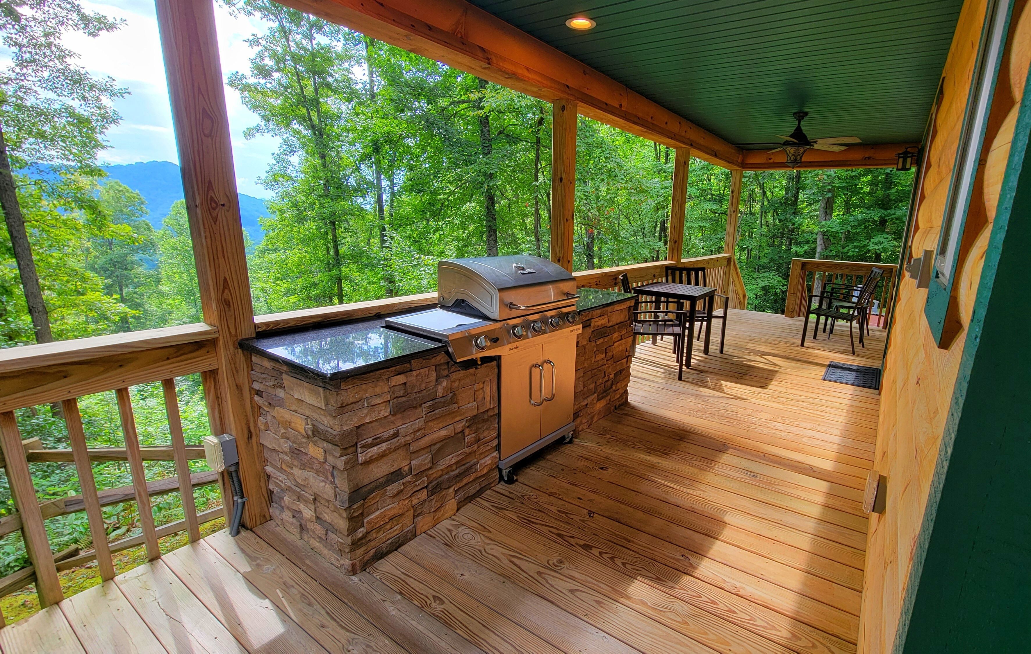 A covered outdoor area with a barbecue grill, stone wall, and wooden deck.