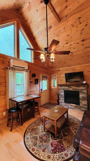 Ein gemütliches Ferienhaus-Interieur mit Essbereich, Kamin, Fernseher und Deckenventilator.