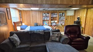 A cozy living room with a sectional sofa, a recliner, and a bookshelf filled with books.