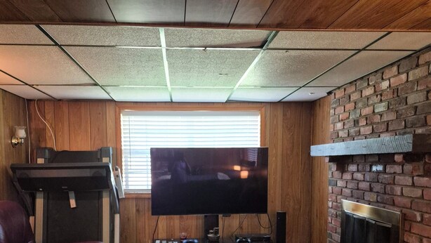 A living room with a television, fireplace, leather chair, and a couch.