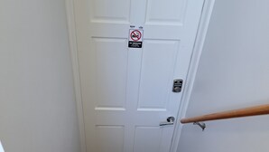 En trappe med trætrapper, der fører op til en hvid dør med et rygeforbudsskilte.