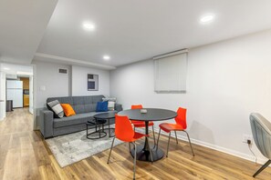 A modern living room with a grey sofa, orange chairs, a round table, and a kitchen in the background. - Cozy Garden apart. 1-bedroom in Franklin Park, near O'Hare and ,,METRO"station (Franklin Park)