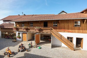 A traditional wooden building with a tiled roof, a balcony with flower boxes, and a cobblestone courtyard where children are playing. - Vrbo Property (Zwiesel)