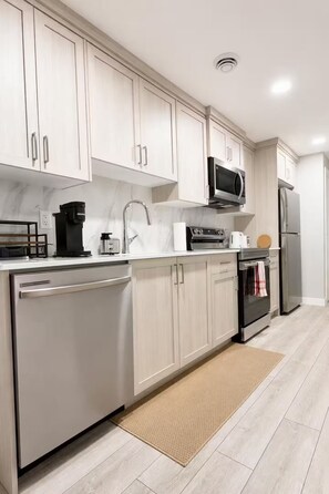 A modern kitchen with white cabinets, stainless steel appliances, and a marble countertop. - Luxury 2‑bed walkout Suite near CalgaryYYC airport (Calgary)