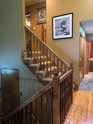 A wooden staircase with carpeted steps leading to a landing. - Spacious 4-bedroom house in charming Oak Grove with AC (Oak Grove)