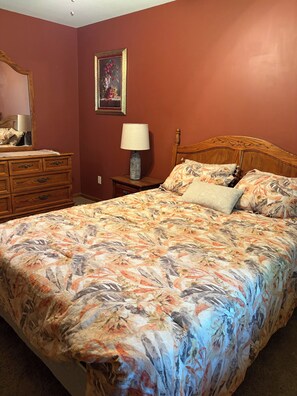 A bedroom with a bed, dresser, nightstand, lamp, and a framed picture on the wall. - Spacious 4-bedroom house in charming Oak Grove with AC (Oak Grove)