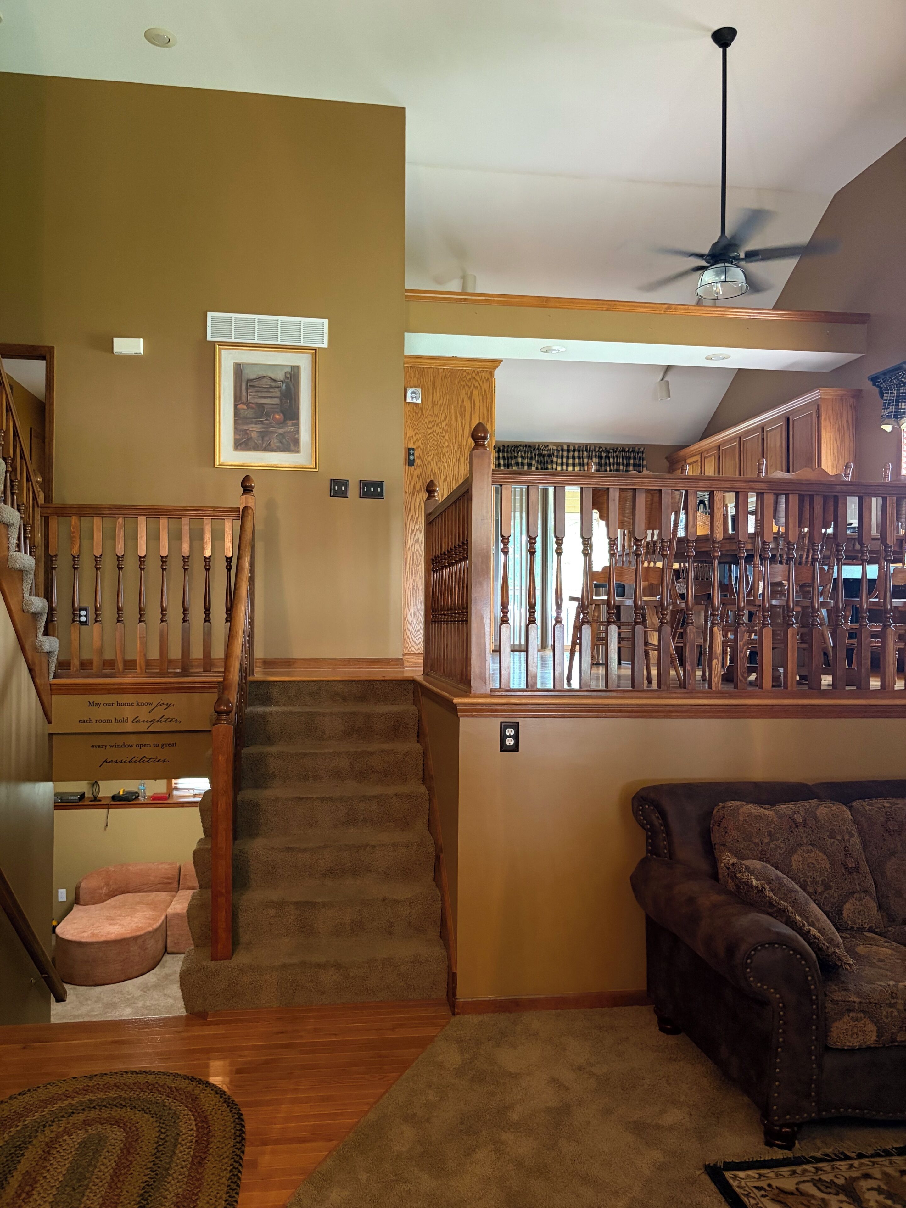 A staircase with a wooden railing, carpeted steps, and a wall-mounted light fixture.