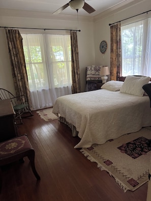 A bedroom with a bed, a chair, a nightstand, a lamp, and a ceiling fan. - Enjoyable 2-bedroom cottage with AC in charming San Antonio. (San Antonio)