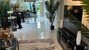 A modern interior with a marble floor, a black entertainment unit, and a dining area with chairs and a table. - CONDO IN DELRAY BEACH (Delray Beach)