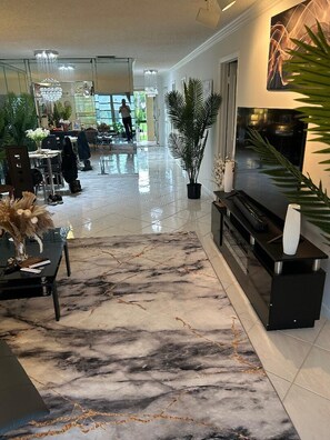 Ein modernes Interieur mit Marmorboden, einer schwarzen Unterhaltungsecke und einer Essecke mit Stühlen und Tisch.