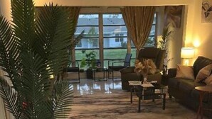 A spacious living area with a tiled floor, a sofa, a coffee table, and a potted plant. - CONDO IN DELRAY BEACH (Delray Beach)