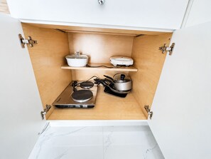A kitchen with a built-in stove, a kettle, and a rice cooker on a shelf. - Cozy 1-Bedroom Studio In Fabulous Orlando With AC and Access To Pool (Orlando)