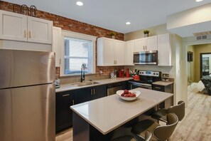 Une cuisine moderne dotée d’appareils électroménagers en acier inoxydable, de meubles blancs et d’un îlot central.