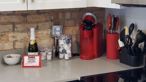 Un comptoir de cuisine avec un paquet de maïs à éclater pour micro-ondes de la marque Kirkland, un appareil à faire éclater le maïs, un bocal de grains de maïs et un récipient rouge pour le maïs éclaté.