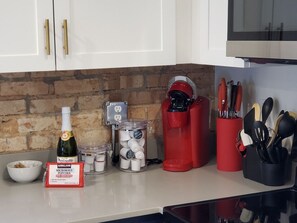 Eine Küchenarbeitsplatte mit einer Flasche Kirkland Mikrowellen-Popcorn, einer Popcornmaschine, einem Glas Popcorn-Körnern und einem roten Popcorndosen.