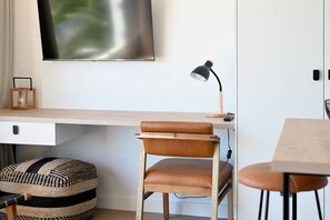 Ein moderner Arbeitsplatz mit Schreibtisch aus Holz, Ledersessel und Wandlampe.
