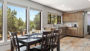 A modern kitchen with a dining area, large windows, and a view of trees. - West Sedona 3BR retreat with game room, patio, and fenced yard. (Sedona)