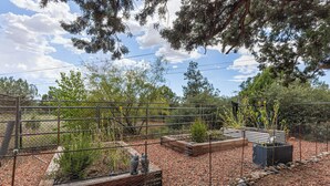 A fenced garden area with various plants and trees. - West Sedona 3BR retreat with game room, patio, and fenced yard. (Sedona)