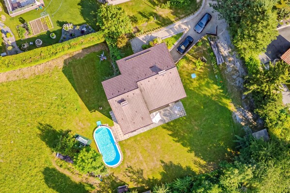 Um imóvel residencial com piscina, uma casa independente com telhado cerâmico e uma entrada por meio de calçada.