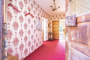 A hallway with patterned wallpaper, a red carpet, and a wooden door with a brass handle. - Villa Evita – Vintage House with Pool in Pohorje, Lovrenc na Pohorju, Slovenia (Lovrenc na Pohorju)