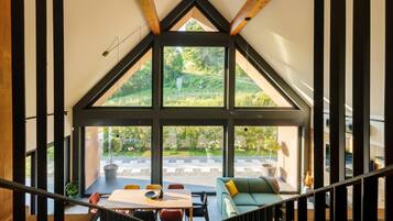 A spacious room with a high ceiling, large windows, and a view of a garden.