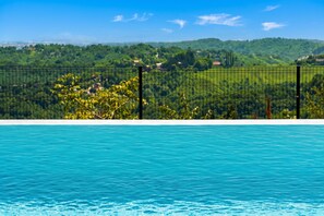A swimming pool with a view of a green landscape and a fence.