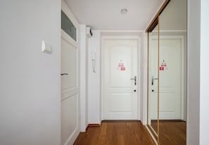 A hallway with a white door, a phone, and a mirror. - Rondo ONZ Homely Apartment (Warszawa)
