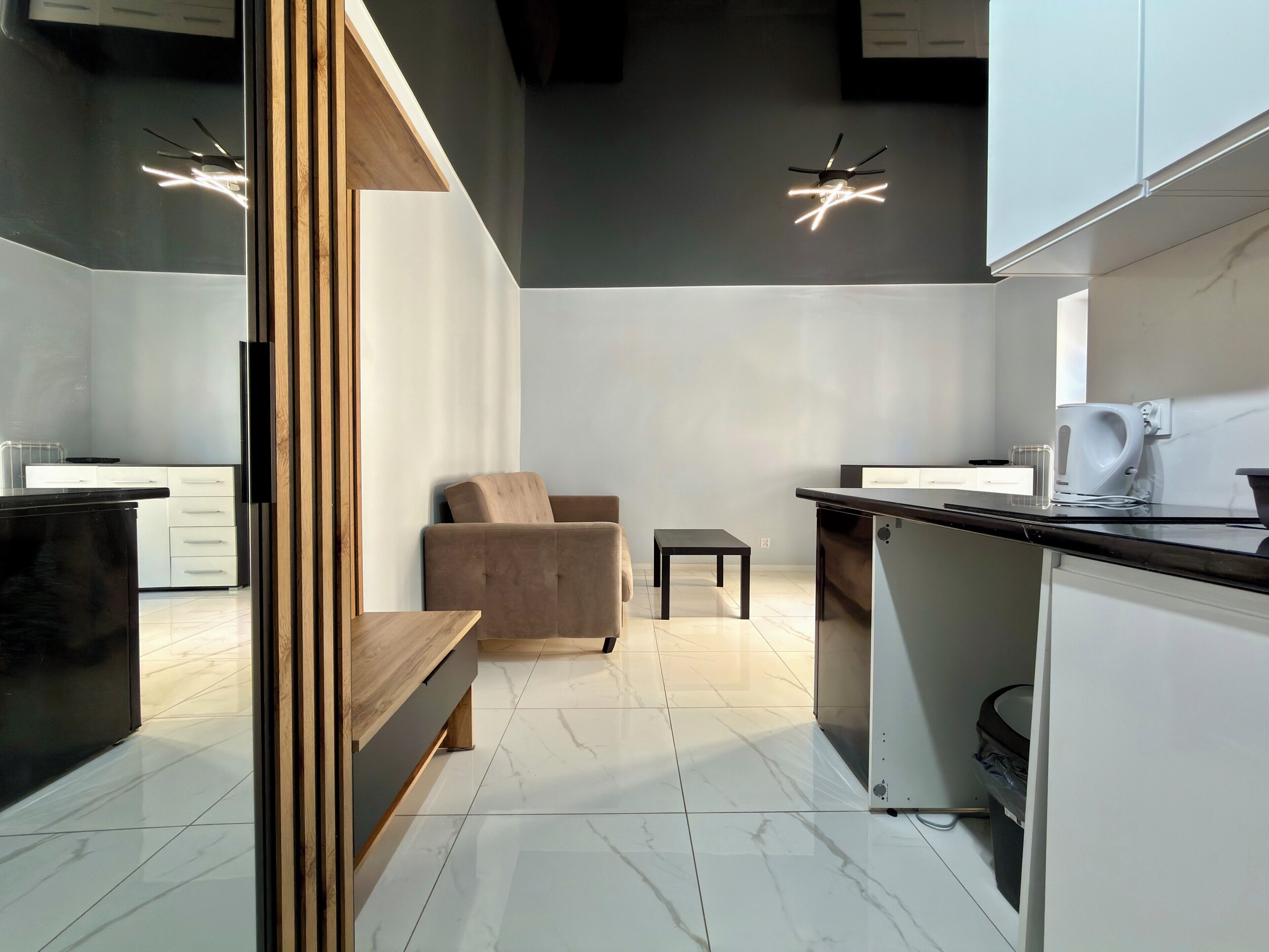 A modern kitchen with a wooden bench, a small table, and a sofa.