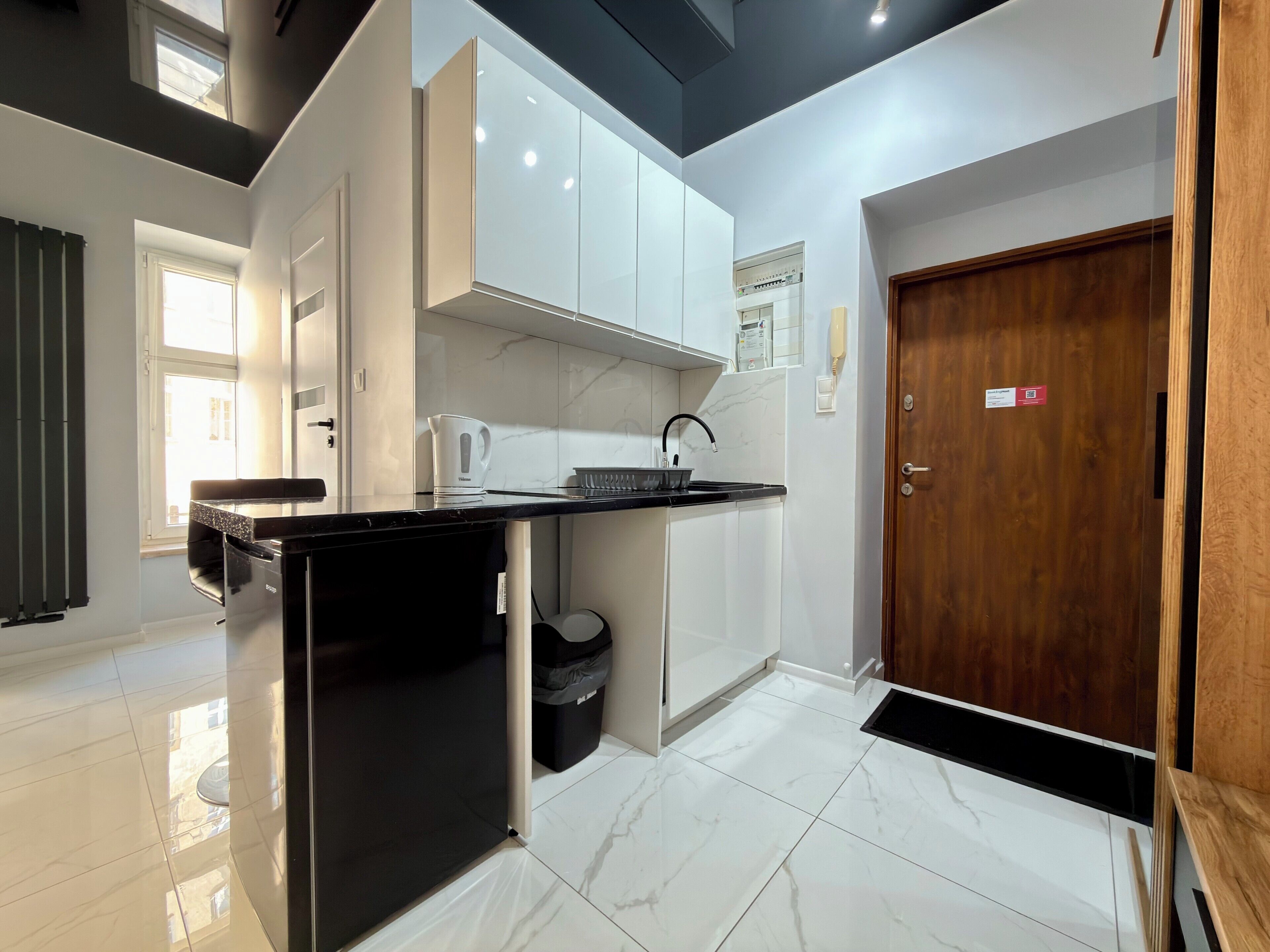 Una cocina moderna con armarios blancos, encimera negra y puerta de madera.