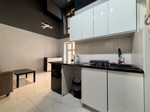 A modern kitchen with white cabinets, a black countertop, and a built-in oven. - Zelwerowicza Central Studio (Wrocław)