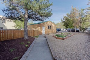 A wooden building with a green roof, a gravel pathway, and a wooden fence. - Cozy 2-bedroom house in peaceful Park City with AC (Park City)