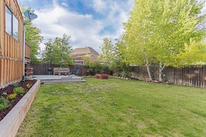 A backyard with a wooden deck, a barbecue grill, and a fenced area. - Cozy 2-bedroom house in peaceful Park City with AC (Park City)