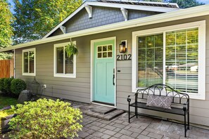 A single-story house with a green door, a mailbox, and the number 2102 on the wall.