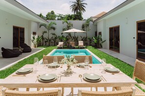 A dining area with a pool, outdoor seating, and lush greenery. - Stylish 3-bedroom villa with king suites near Lamai Beach (Chang Wat Surat Thani)