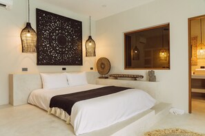 A bedroom with a large bed, two hanging light fixtures, a decorative wall piece, a round mirror, and a small shelf with a statue. - Stylish 3-bedroom villa with king suites near Lamai Beach (Chang Wat Surat Thani)
