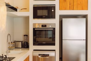 A kitchen with a Bosch microwave, oven, and dishwasher, a stainless steel refrigerator, and a sink with a modern faucet.