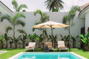 A pool area with two lounge chairs and a large umbrella, surrounded by lush tropical plants. - Stylish 3-bedroom villa with king suites near Lamai Beach (Chang Wat Surat Thani)
