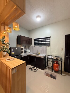 A compact kitchen with a refrigerator, sink, and gas stove.