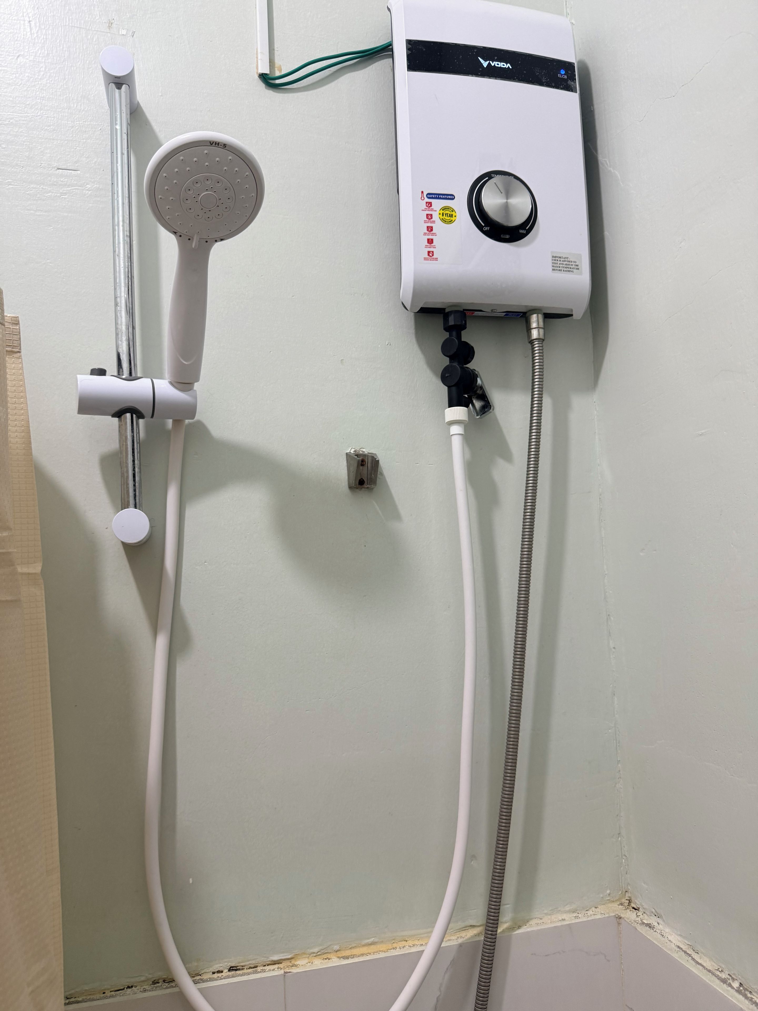 A shower unit with a handheld showerhead and a wall-mounted control panel.